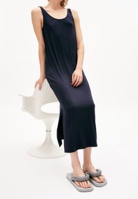 Marinblå ärmlös maxiklänning i mjukt tyg med en sidofåra. Kombinerad med gråa sandaler med slits som har en ögla-design. Minimalistisk stil.