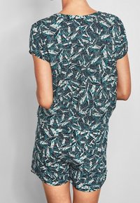 Short-sleeve romper made of lightweight fabric; features a dark teal and white leaf pattern with a relaxed fit and gathered waist.