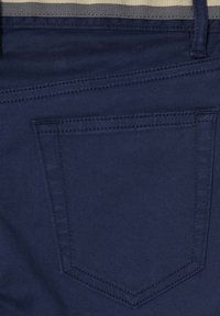 Tessuto in denim blu navy con una tasca posteriore caratterizzata da un motivo di cuciture diagonali. Texture liscia con una vestibilità standard.