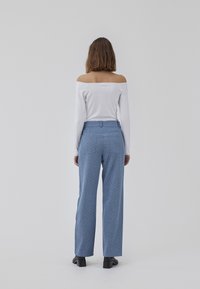 Light blue patterned pants with a straight fit and high waist, paired with a white off-the-shoulder top. Material appears smooth with a subtle sheen.