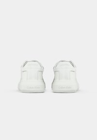 White leather sneakers with a smooth texture, featuring a padded collar and embossed branding on the heel and side for added detail.