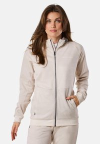 Light beige zip-up hoodie made of soft fabric, featuring a high collar, side pockets, and logo detail. Ribbed cuffs at the sleeves.