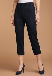 Zwarte geribbelde cropped broek met een elastische tailleband, met zijnaad. Gecombineerd met marineblauwe hoge hakken. Gladde textuur.