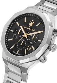 Orologio in acciaio inossidabile argento con quadrante nero, dettagli dorati e sottodials cronografici. Presenta una cassa ottagonale e un bracciale in metallo.