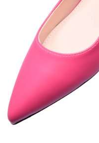 Pump a punta in pelle sintetica rosa con una superficie liscia e rivestimento interno nude, dotata di suola nera e dettagli di cucitura minimi.