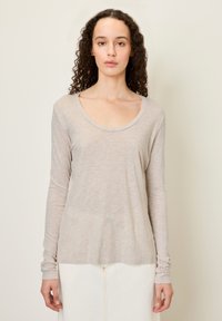 Svetlo béžová dlhá košeľa s okrúhlym výstrihom. Mäkká, tenká tkanina s jemne štruktúrovaným povrchom. Má priliehajúce rukávy a voľný strih.