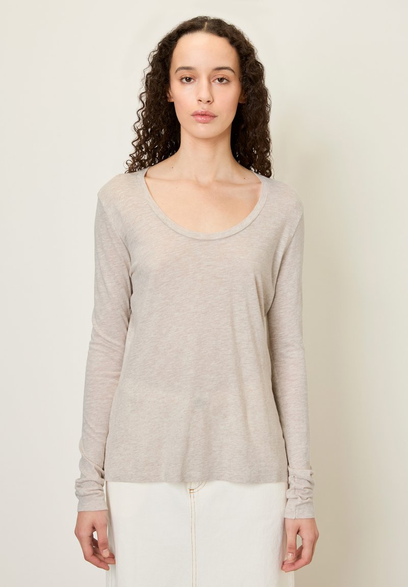 Svetlo béžová dlhá košeľa s okrúhlym výstrihom. Mäkká, tenká tkanina s jemne štruktúrovaným povrchom. Má priliehajúce rukávy a voľný strih.