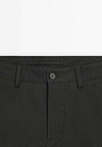Pantalon vert foncé avec un design classique, fermeture par boutons et passants pour ceinture. Le tissu est lisse avec peu de détails de couture.