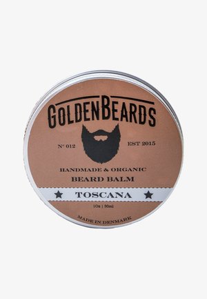 Lata de metal de bálsamo para barba con una etiqueta marrón cobre. Presenta un gráfico de barba negra, una franja blanca y texto que incluye "Hecho a mano y orgánico."