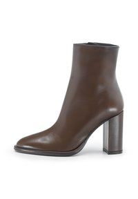 Stivale in pelle marrone con punta affusolata, gambale stretto e tacco a blocco alto. Texture liscia con pochi dettagli di cucitura.