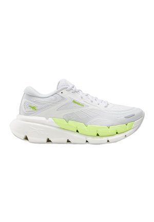 Chaussure de sport blanche avec tige texturée, accents vert néon sur la semelle intermédiaire, semelle épaisse segmentée et lacets blancs, vue de profil.