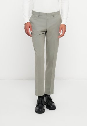 Lys grå skreddersydde bukser med slim fit, med en glatt tekstur og beltehemper. Båret med svarte snørestøvler.