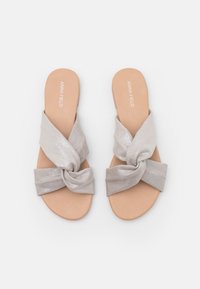 Srebrne klapki z węzłem z miękką, teksturowaną cholewką i gładką, tanową podeszwą. Prosty, płaski design bez widocznych elementów metalowych czy zdobień.