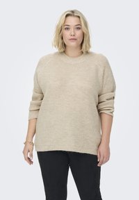 Beige gestrickter Pullover mit Rundhalsausschnitt, überschnittenen Schultern und gerippten Bündchen. Die Textur ist weich, mit einer lockeren Passform und feinem Muster.