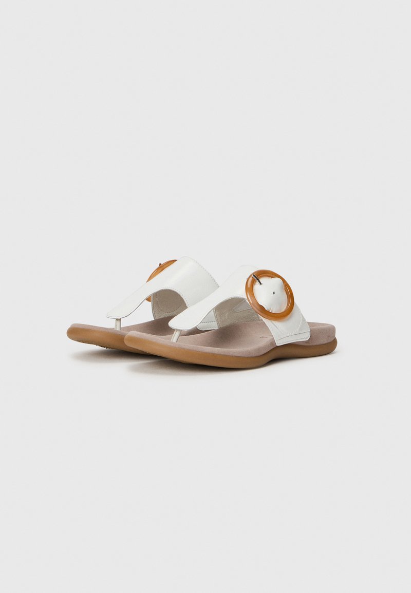 Witte sandalen met een bruine cirkelvormige accenta, met een teenpostontwerp en een gevoerd zool, weergegeven op een effen achtergrond.