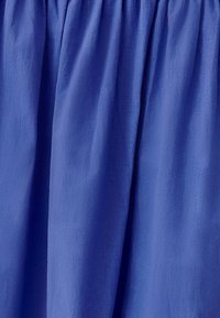 Tessuto blu royal con texture arricciata, finitura liscia e aspetto leggero. Il materiale si drappeggia dolcemente senza decorazioni.