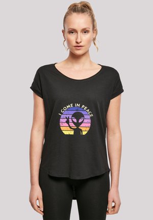 Black short-sleeve t-shirt with a rounded neckline, featuring a colorful alien graphic and text "I COME IN PEACE" in a retro style.