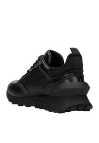 Scarpe sportive nere con una parte superiore in materiale sintetico liscio, dettagli perforati, suola spessa e linguetta posteriore testurizzata per facilitare l'inserimento.