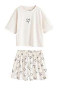 Világos bézs színű pamut pizsama szett, rövid ujjú felsővel, amelyen szív grafika található, és hozzáillő rövidnadrággal, amelyen szív minták díszítik.