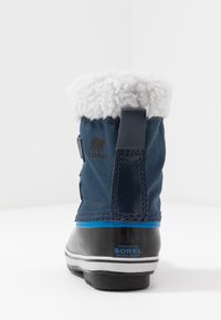 Stivale invernale blu navy con colletto in finta pelliccia, suola in gomma e logo Sorel. Presenta una tomaia in tessuto testurizzato e una striscia blu di accento.
