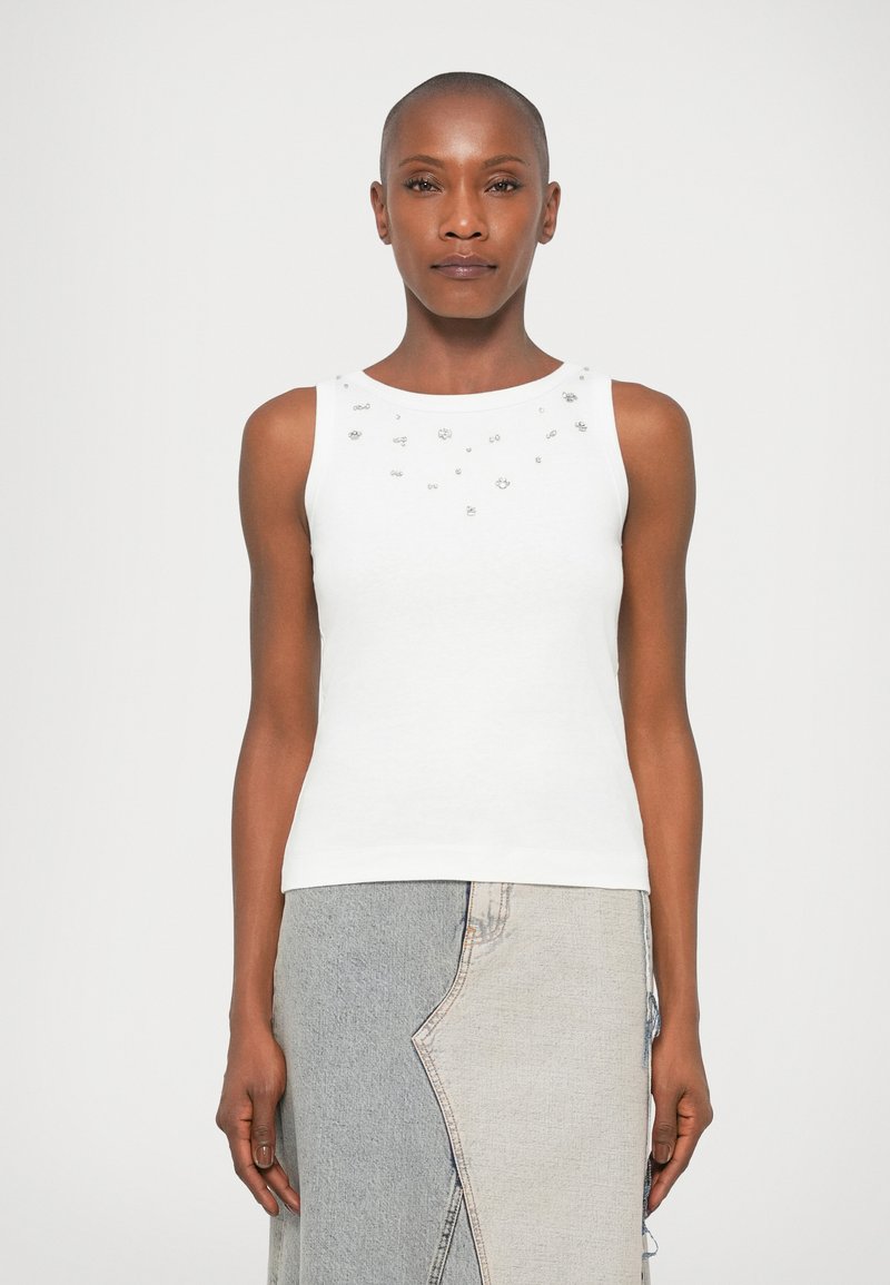 Fehér ujjatlan felső, díszes ezüst díszítésekkel a nyakrészen. Puha anyagból készült, testhezálló fazonban.