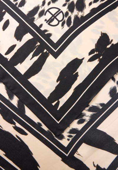 Tissu noir et beige à motifs avec imprimé animal abstrait et lignes noires croisées présentant un logo circulaire stylisé avec des lettres.