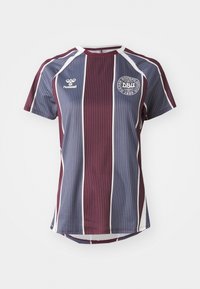 Maroonsinised ja sinised triibulised spordisärk lühikeste varrukatega. Omab ümmargust kaela, valgeid aktsente ja ümmargust logo rinnal.
