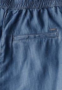 Shorts in denim azzurro con vita elasticizzata, dotati di una tasca posteriore e di un piccolo etichetta del marchio. Texture liscia e design casual.