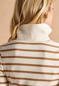 Top z bavlnenou zmesou s bielo-hnedým pruhovaným vzorom, s klasickým golierom a rebrovanou textúrou. Z pohľadu zozadu je vidieť jemnú látku.