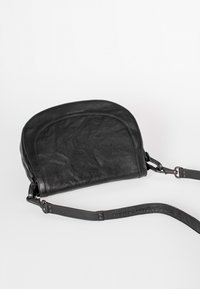 Borsa a tracolla nera in pelle con parte superiore curva, finitura texturizzata, tracolla regolabile e un accento con logo impresso lungo la tracolla.