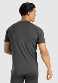 Donkergrijze sportt-shirt van soepel, rekbaar materiaal, met korte mouwen en een getailleerd ontwerp met een ronde halslijn.