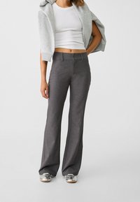 Pantalons gris ajustés avec une coupe droite. Comprend deux boutons à l'avant, une texture lisse et une taille mi-haute.