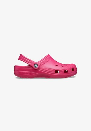 Pink plastic clog featuring a closed toe, back strap, ventilation holes, and textured sole for grip. Smooth, lightweight design.