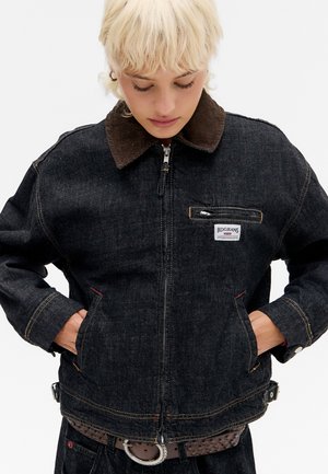 Veste en denim noire avec un col en velours côtelé, fermeture éclair avant, poche poitrine et détails en couture jaune ; coupe décontractée avec poches latérales.