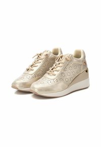 Sneakers con zeppa beige con motivo floreale perforato, accenti metallici lisci, lacci piatti e supporto per la caviglia imbottito. Suola in gomma.