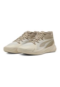 Beige træningssko med et struktureret mesh-overdel, mønstrede detaljer og en polstret krave. Har en solid gummisål og snøresystem.