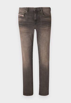Skinny jeans in a faded black color, featuring five pockets, belt loops, and a zip fly. Material shows slight texture with subtle whiskering.