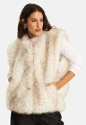 Faux bont vest in licht beige met een zachte textuur, voorzien van een coltruim ontwerp en twee zijzakken. Draag het over een witte lange mouwen shirt.