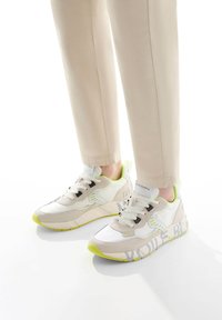 Sneakers sportivi in beige, bianco e verde neon, caratterizzati da un mix di materiali lisci e testurizzati con dettagli del logo sul lato.