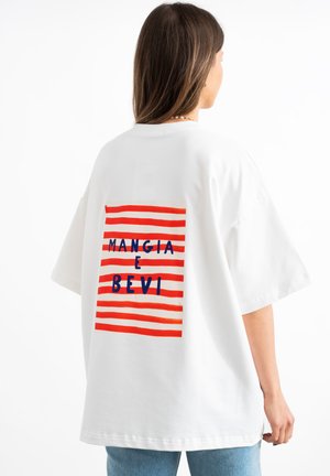 T-shirt blanc surdimensionné avec un graphique à rayures rouges et bleues et le texte "MANGIA E BEVI" au dos. Matériau en coton doux, coupe décontractée.