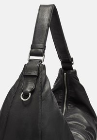 Bolso de piel negra con una correa ancha, herrajes plateados y un compartimento con cremallera. Presenta una superficie texturizada y un acabado suave.