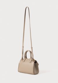 Borsa a mano in pelle beige con doppi manici e una lunga tracolla staccabile. Presenta una texture liscia e un design minimalista.