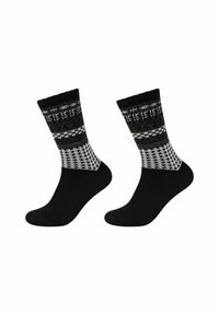 Calzini neri con una sezione alla caviglia grigia e bianca a motivi. Presentano un design in maglia con forme geometriche e una consistenza liscia.