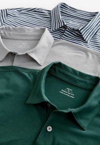 Tre poloshirts med krave: mørkegrøn, lys grå og marineblå stribet. Hver har en knaplukning og blødt stof med plejelabels synlige.