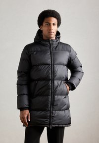 Crna puffer jakna s kapuljačom, sa kviltanim panelima, džepovima na zatvarač i elegantnim dizajnom. Mat finish i izdržljiv materijal.