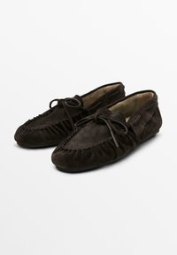 Dark brown suede moccasin shoes with a rounded toe, ruffled design, and tied lace detail. Flat sole, soft texture, and casual style.