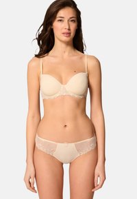 Beige bh med spetsdetaljer, vadderade kupor och justerbara axelband, tillsammans med matchande bikiniunderkläder som pryds av blommig brodyr.