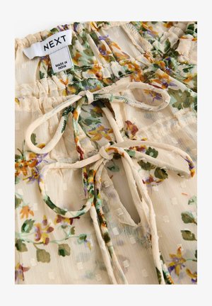 Lengvas, kreminės spalvos bliuskė su violetiniais, geltonais ir žaliais gėlių raštais. Yra susiraukšlėjimų detalės ir kaklo raištelis.