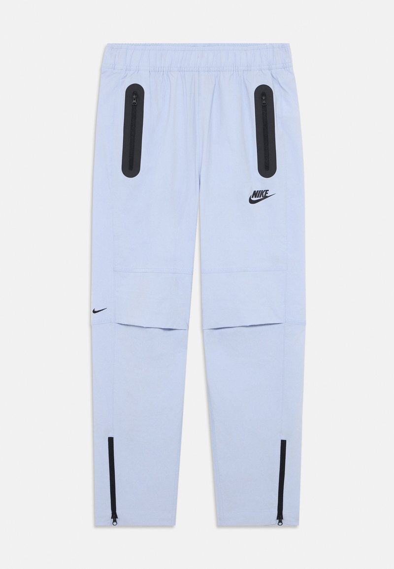 Gaiši zili Nike sporta bikses ar melnajām kabatām ar rāvējslēdzējiem uz augšstilbiem, Nike logo labajā augšstilbā un kreisajā ikrā, elastīga josta un rāvējslēdzēji uz potītēm.