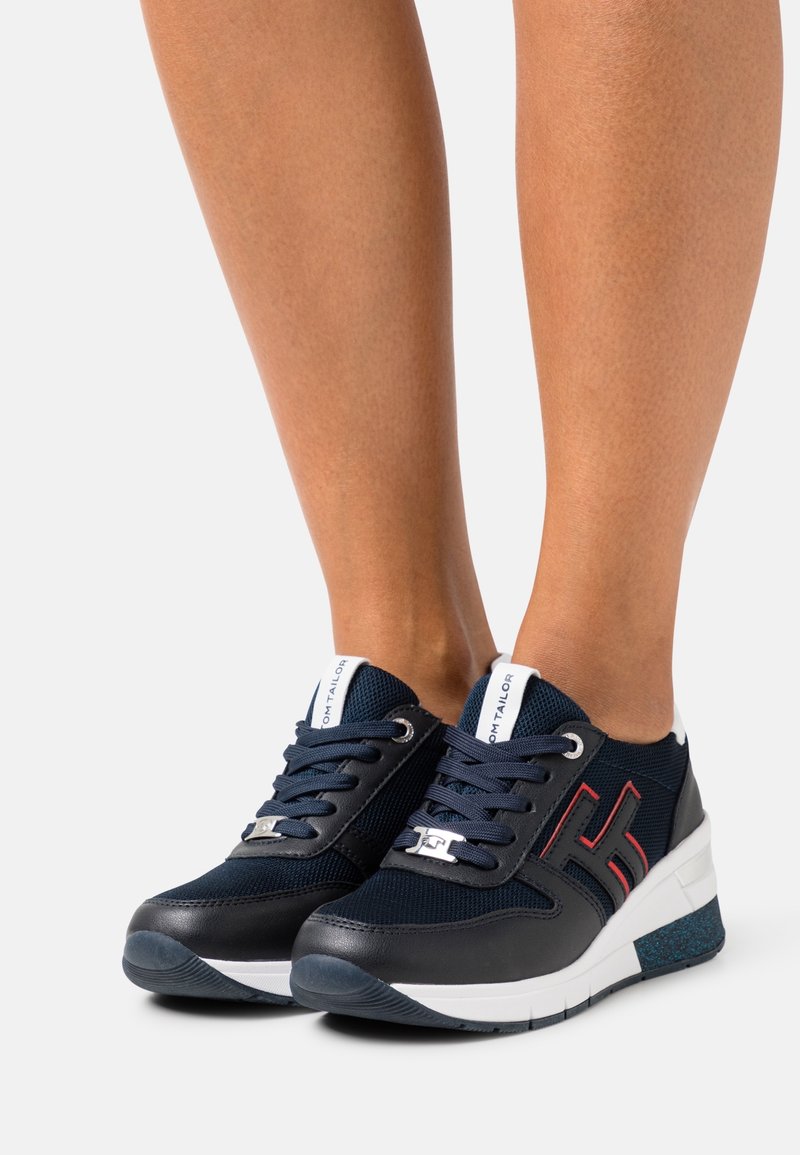 Baskets bleu marine durables avec une combinaison de mesh et cuir synthétique, une semelle blanche parsemée de taches bleues, et des accents rouges contrastants sur le côté.